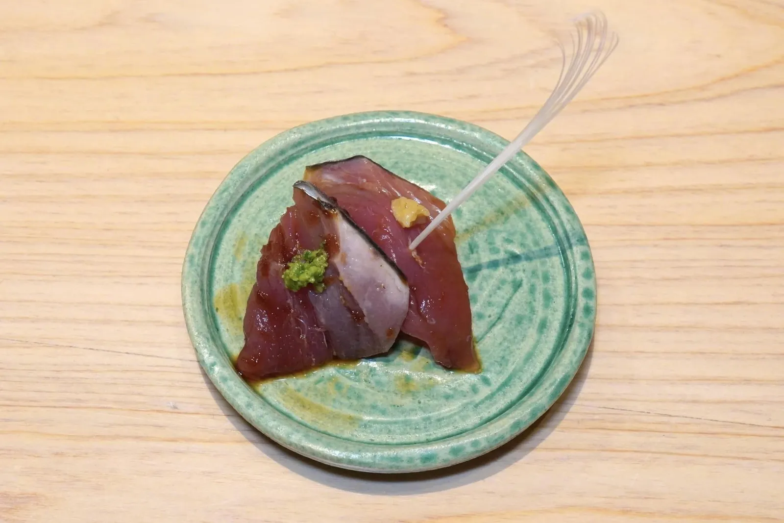 Katsuoปลาโอหมักกับซอสสูตรพิเศษของเชฟ นอกจากนี้เชฟยังเบิร์นไฟที่หนังปลาจนหอม ชิ้นหนึ่งท็อปด้วยต้นหอมสับ อีกชิ้นหนึ่งท็อปด้วยขิงแบะมัสตาร์ด จากนั้นตกแต่งด้วยไม้จิ้มที่เตรียมมาจากกระดูกปลาโอ (14/20)