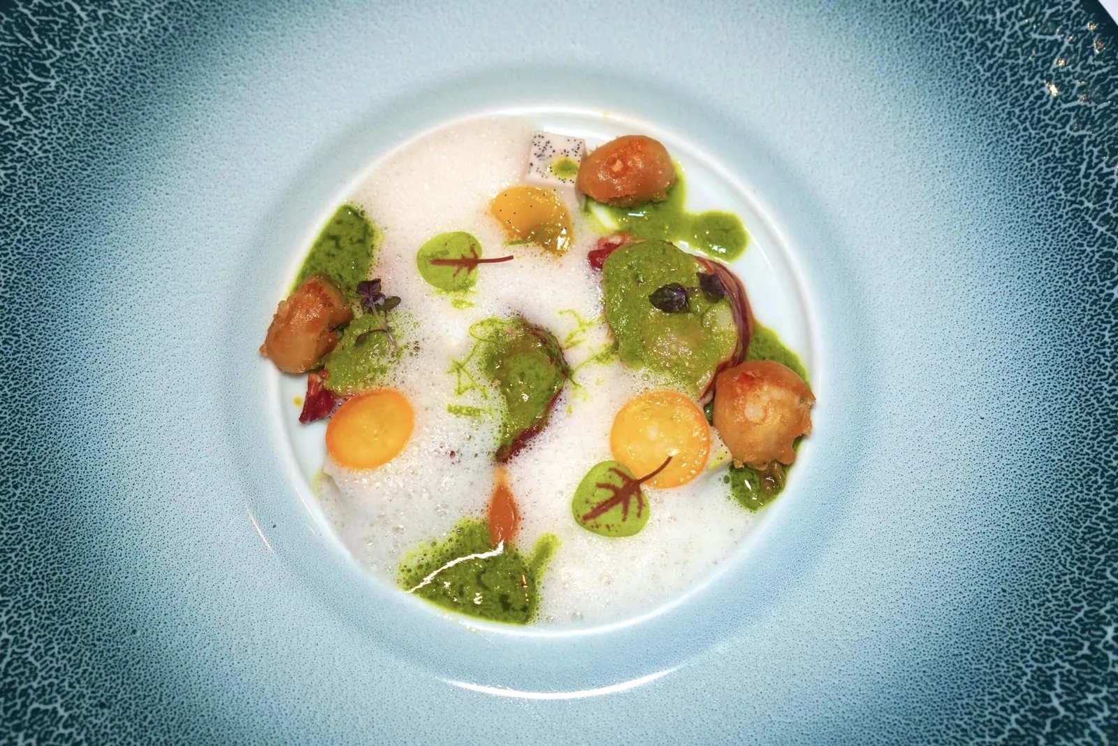 Homard nacré au curry vert, Bisque épicée coco-kumquatกุ้งล็อบสเตอร์ที่เตรียมมาสุกกำลังดีสังเกตจากเนื้อกุ้งแต่ละชิ้นที่นุ่มมาก ๆ จนเกือบจะละลายในปาก ข้าง ๆ กันคือกุ้งชุบแป้งทอดจนกรอบสร้างมิติทางเนื้อสัมผัส เชฟจับคู่มากับซอสแกงเขียวหวานชวนนึกถึงเมนูแกงที่ขึ้นชื่อที่สุดจานหนึ่งของประเทศไทย อโรม่าของเครื่องแกงผสานเข้ากันกับความหอมของกะทิและวานิลลาได้อย่างไร้ที่ติ นอกจากนี้ยังมีความเผ็ดเบา ๆ ของพริกแกง ความซิตรัสของ Kumquat ความหวานกลมกล่อมของผลแก้วมังกร และความหวานละมุนที่ได้จากมะม่วงสุก สุดท้ายคือซอสที่เกิดจากการเคี่ยวกะทิและ Citronella เข้าด้วยกัน (20/20)