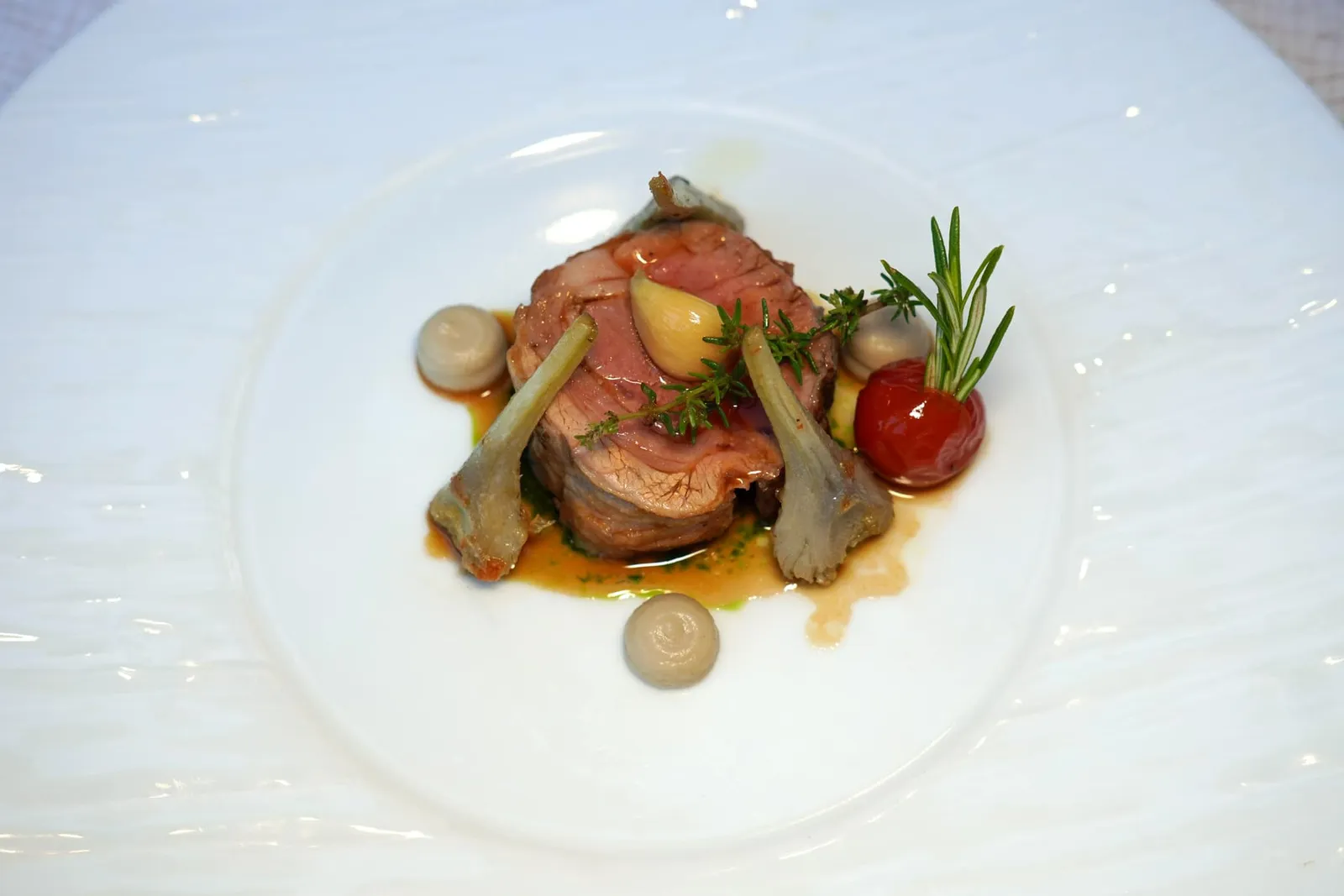 Selle d'agneau fermier du Quercy rôtie au thym et à l'ail, pesto à l'ail des ours, artichauts violets en barigouleเนื้อแกะส่วนสันหลังหรือ Saddle จากเมือง Quercy ย่างกับใบไทม์และกระเทียมจนนุ่มและหอมกรุ่นขนาบด้านข้างด้วยชิ้นอาร์ติโชคม่วงที่เสิร์ฟมาในสไตล์ Barigoule ด้านบนท็อปด้วยชิ้นกระเทียม เชฟเติมแต่งความหวานด้วย Purée ของอาร์ติโชค ชิ้นมะเขือเทศให้รสเปรี้ยวฉ่ำมาตัดกันกับซอส Lamb Jus รสชาติเข้มข้น (16/20)
