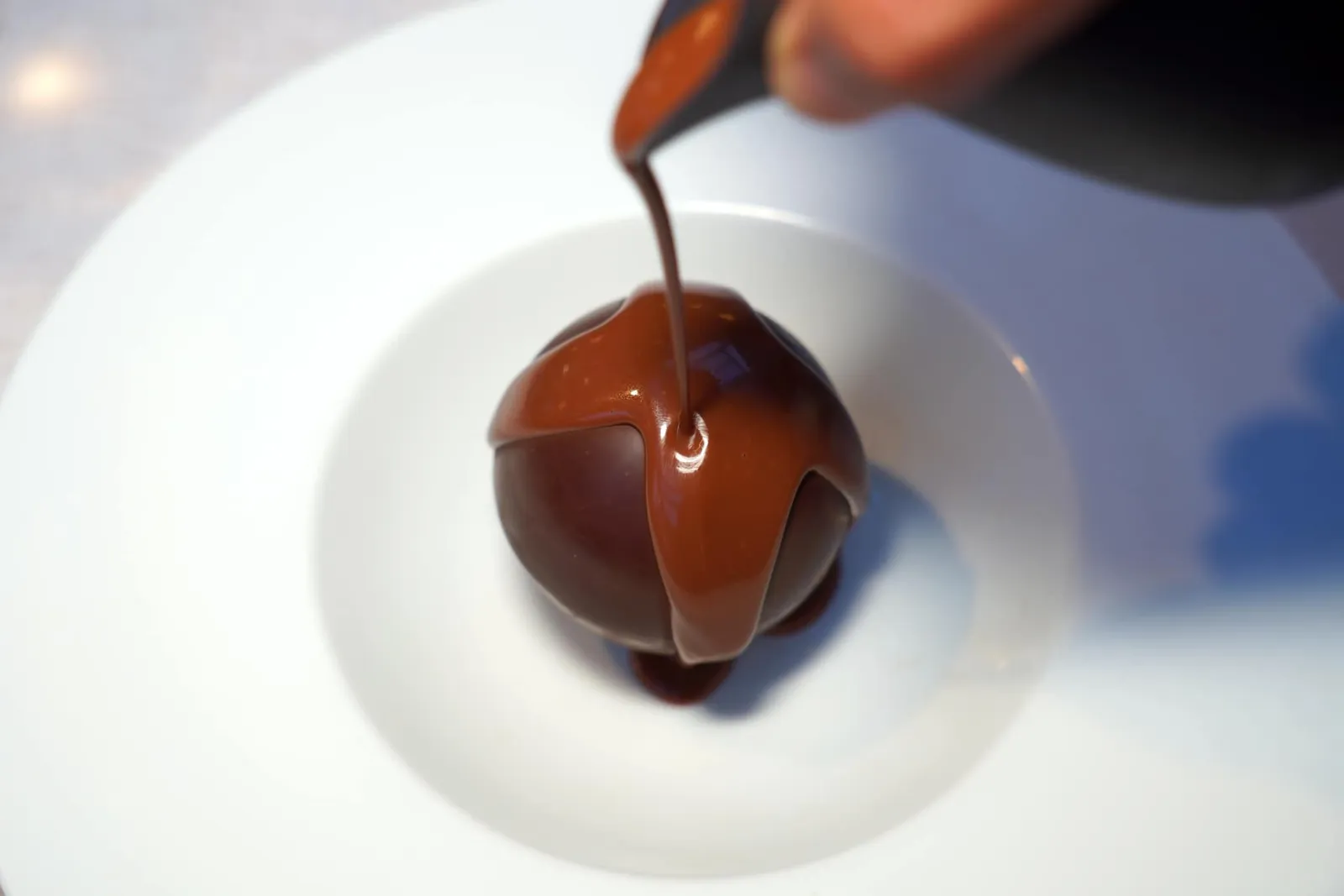 Sphère chocolat, crémeux framboise, gelée citronelle, streusel amande, glace vanille, sauce chocolat caraïbeของหวานจานแรกคือช็อกโกแลตเสิร์ฟมาในรูปแบบของสเฟียร์ทรงกลม (16/20)