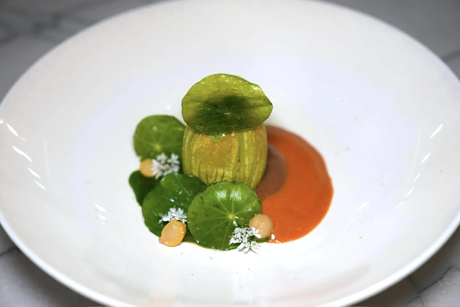 ZUCCHINI FLOWERstuffed, Beauce chickpeas, nasturtium, Loire Valley moleดอกซูคินี่จากสวน Fleur de Loire Gardens ของทางร้าน ด้านในสอดไส้ซูคินี่ครีมช่วยสร้างความแตกต่างของเนื้อสัมผัส ด้านล่างรองด้วย Mole ที่เชฟเปลี่ยนจากสไตล์ Mexican ต้นตำรับมาเป็นสูตรของตัวเองโดยใช้ถั่วลูกไก่จากแถบลุ่มแม่น้ำ Loire แล้วใช้ชื่อว่า Loire Valley Mole ผสมผสานกับอโรมาของพริกหวาน (18/20)