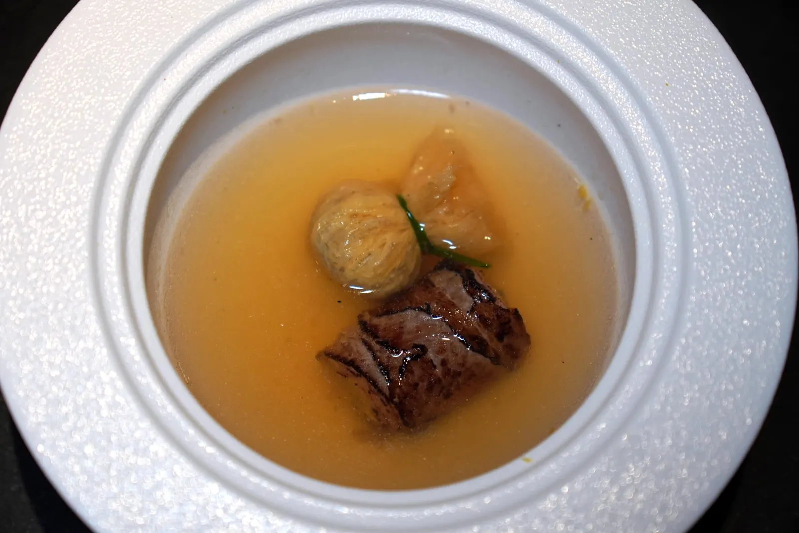 ODENJapanese Dashi | Capsicum Extract | Aged Ribeye | Yuba Wontonเชฟตั้งใจนำเสนอโอเด้งในรูปแบบของตัวเองโดยใช้เนื้อวัวไทยวากิวส่วนซี่โครงบ่มแล้วนำมาแล่เป็นชิ้นบาง ๆ จากนั้นเบิร์นจนหอม เชฟนำมาพันม้วนกับ Gobo ที่ผ่านการเคี่ยวแล้วปรุงรสด้วย Mustard ฉุน ๆ อีกฝั่งหนึ่งคือ Yuba หรือฟองเต้าหู้ที่ด้านในบรรจุ Compressed Gobo มีรสหวานโดดเด่น เชฟเสริมด้วย Gobo Espuma และพริกไทย Sancho เล็กน้อยแล้วห่อม้วนมาเป็นถุง รอบ ๆ คือซุปดาชิที่ขึ้นมาจากผักหัวและผักรากต่าง ๆ ตุ๋นกับสาหร่าย Kombu และ Katsuobushi ช่วยเพิ่มความอุมามิ นอกจากนี้เชฟยังใส่ความฉุนที่ได้จากน้ำสต๊อกพริกหวานเผาลงไปด้วย (14/20)