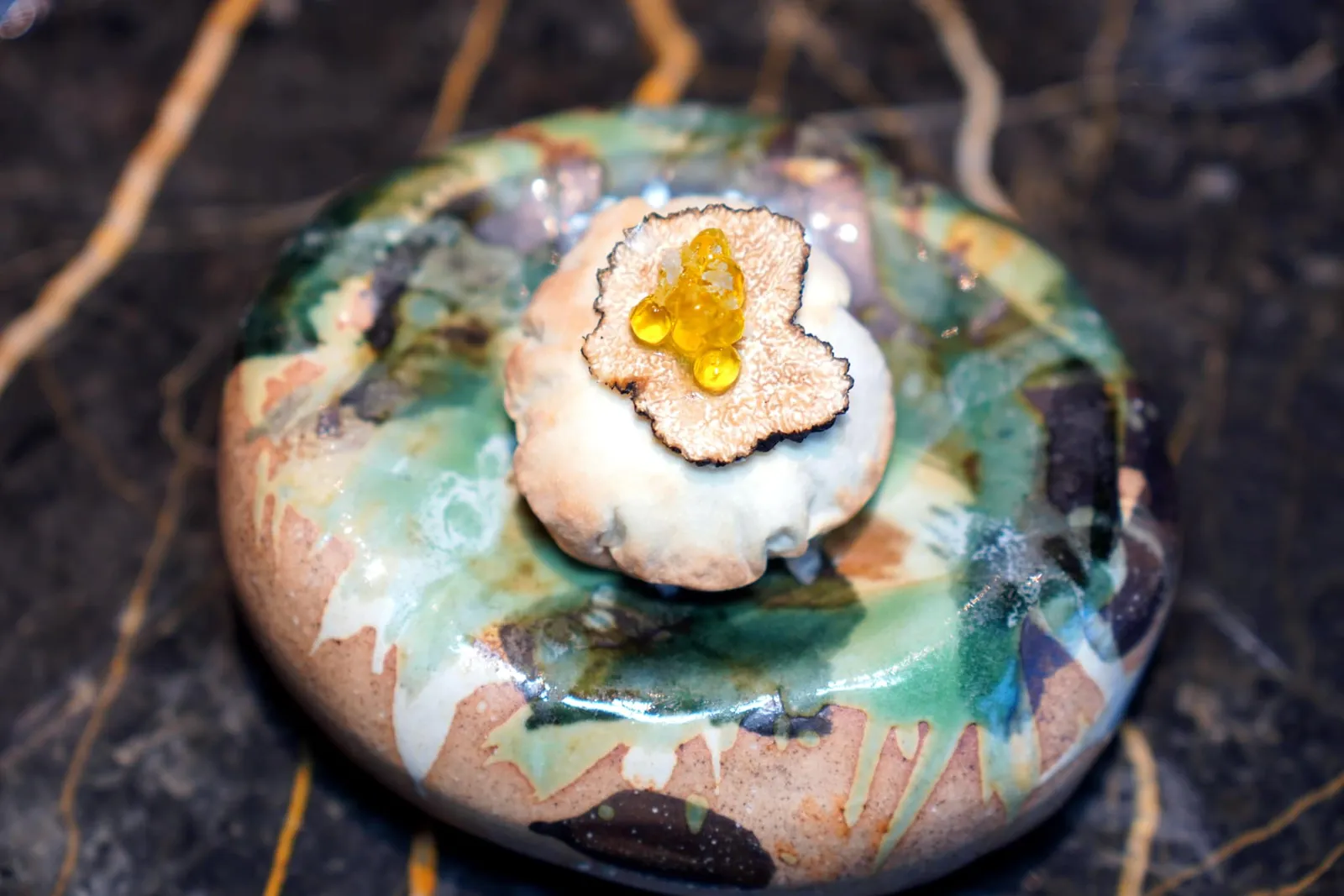 Truffle Manchego Pillow (2 Pc)Explosion of truffle and cheese topped with sliced truffleเชฟนำเสนอ Pillow ที่เราพบเจอในวันนี้มีความเหนียวอยู่เล็กน้อย ด้านในคือชีส Manchego ของประเทศสเปนผสมผสานกันกับทรัฟเฟิล จากนั้นนำเข้า Espuma จนได้เนื้อสัมผัสเบาก่อนจะยัดเข้าไปใน Pillow ด้านบนท็อปด้วยทรัฟเฟิลฝานบางและคาเวียร์ทรัฟเฟิลออยเตรียมมาในรูปแบบโมเลกุลนั่นเอง (13/20)