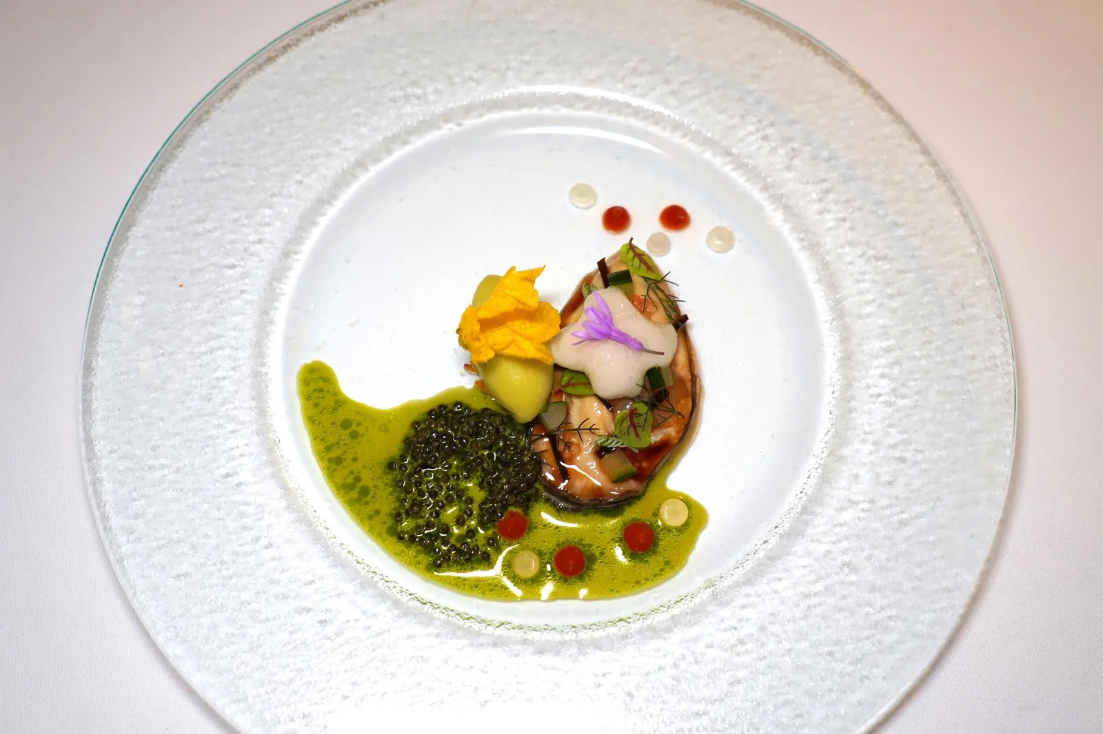 🥄 STARTEROstra Regal Gold Oyster | Cucumber Sorbet | Kombu | Fingerlime | Yuzu & Chilli Condiment | Crispy Shallot | Acacia & Caviar Emulsionหอยนางรม Ostra Regal Gold Oyster จากประเทศฝรั่งเศสย่างจนเนื้อรัดตัวพอเหมาะเสิร์ฟมากับโฟมของหอยลายให้อโรมาของทะเล ข้าง ๆ คือซอร์เบท์แตงกวาที่ไม่มีกลิ่นเขียวจนเกินไปผสานเข้ากับความฉุนเบา ๆ ของหอมเจียว เชฟยังปรุงแต่งรสและกลิ่นด้วยยูซุและพริก ในจานมีความเปรี้ยวของมะนาวนิ้วมือ จากนั้นจบด้วยการราดซอสอีมัลชั่นที่มีความฉุนเบา ๆ ผสานเข้ากับความเค็มและกลิ่นของทะเลของ Kristal Caviar ลงไปในจาน (15/20)