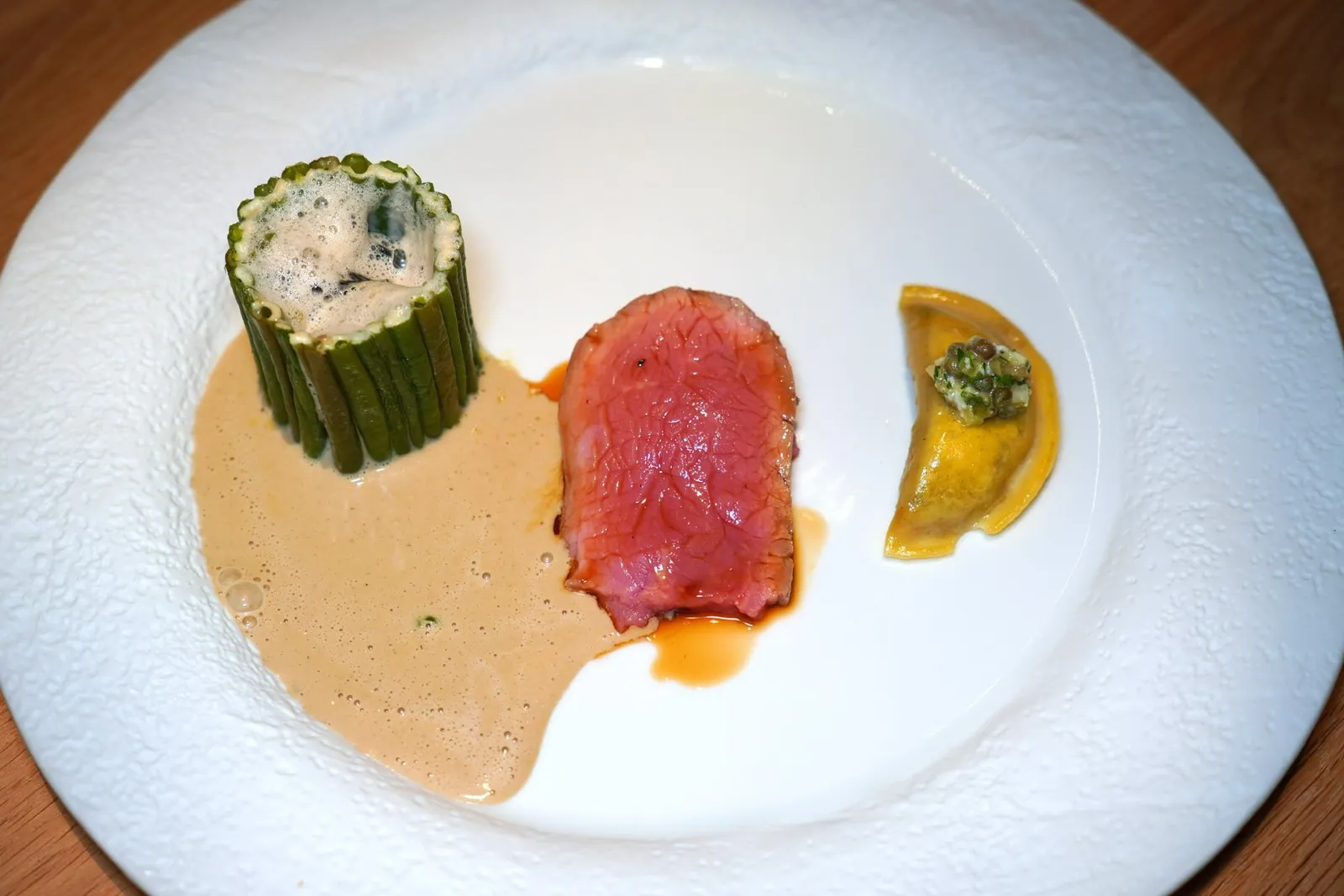 Pièce de veau de Christine Castello cuite « Josper », fagot de haricot vert, blanquette de champignons, raviole potagère, jus de déglaçage à la nepitaเชฟวางซ้อนทับกันมารวม 3 ชิ้น ข้าง ๆ กันคือถั่ว Green Beans วาวเรียวกันมาเป็นกรง ด้านในประกอบไปด้วย Mushroom Blanquette จากนั้นพนักงานจะเทราดซอสครีมเห็ดลงไปในจาน (17/20)
