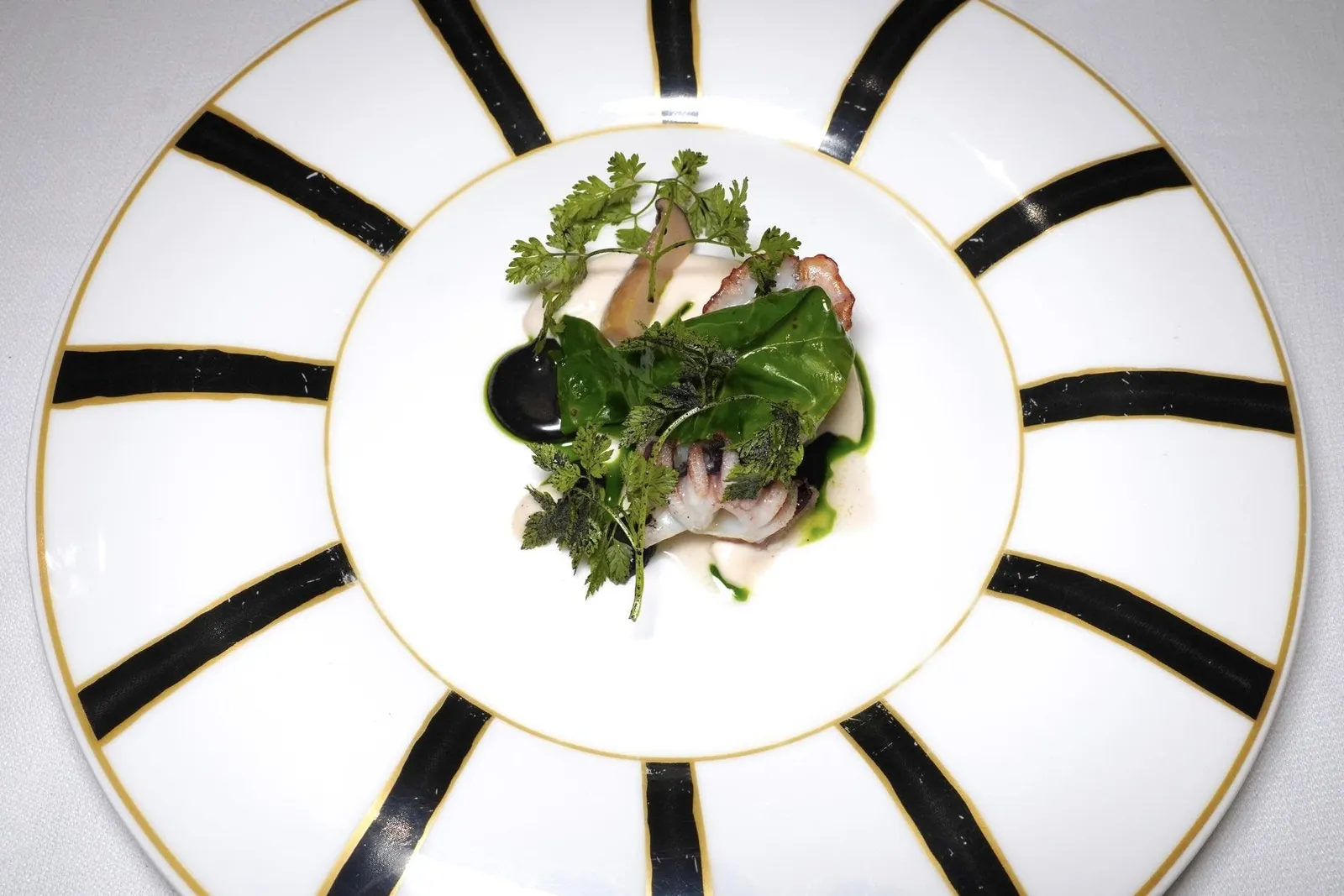 CHARGRILLED CUTTLEFISHสุดยอด Signature Dish ประจำร้านคือหมึกกระดองที่ผ่านการย่างจนสุกและรมควันออกมาได้อย่างไร้ที่ติสังเกตจากเนื้อสัมผัสที่มีความนุ่มและเด้งไปพร้อม ๆ กันโดยไร้ซึ่งความเหนียว ซอสสีขาวรอบ ๆ เตรียมมาจากไข่หมึกให้ความครีมมี่ ส่วนซอสสีเข้มเตรียมมาจากดีหมึก นอกจากนี้จานที่ใช้เสิร์ฟคอร์สนี้ยังได้มาจาก Geminiano Cozzi ซึ่งเป็นผู้ผลิตเครื่องเซรามิคที่มีชื่อเสียงที่สุดของนคร Venice อีกด้วย (18/20)