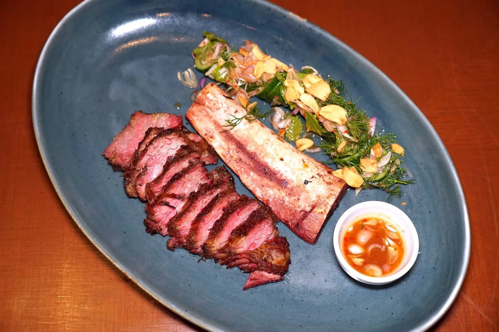 Beef Short Ribยำซี่โครงเนื้อย่างเนื้อวัวส่วนซี่โครงเสิร์ฟมาจานใหญ่กับสลัดเคียงและซอสน้ำยำข้าง ๆ กัน