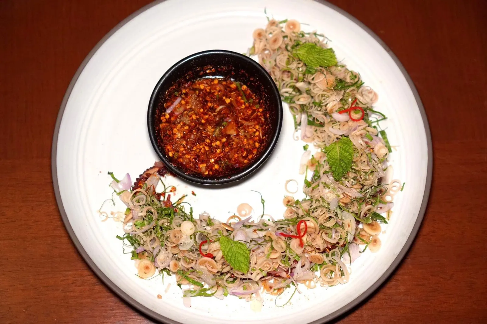 Octopus Larbลาบหนวดปลาหมึกย่างทางร้านนำหนวดหมึกยักษ์มาหั่นเป็นชิ้นบาง ๆ คลุกเคล้ากับตะไคร้ที่ค่อนข้างเยอะ ข้าวคั่ว และสมุนไพร อย่าลืมราดซอสรสชาติจัดจ้านลงไปด้วย