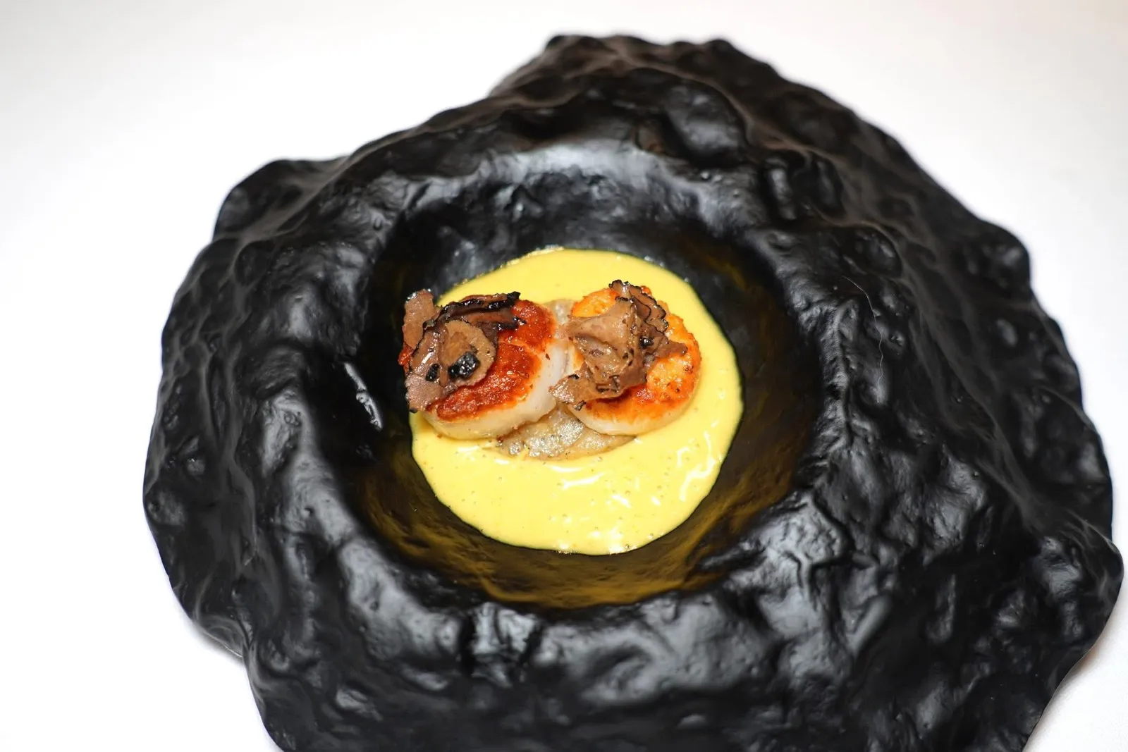 Capesante, patate ratte al tartufo nero e spezieหอยเชลล์จี่มาจนสุกเสิร์ฟมาคู่กันกับมันฝรั่งสายพันธุ์ Ratte รองอยู่ด้านล่าง รอบ ๆ คือซอสที่ผสมผสานเครื่องเทศและ Curcuma หรือขมิ้นลงไปด้วย ด้านบนท็อปด้วยเห็ดทรัฟเฟิลหอม ๆ (15/20)