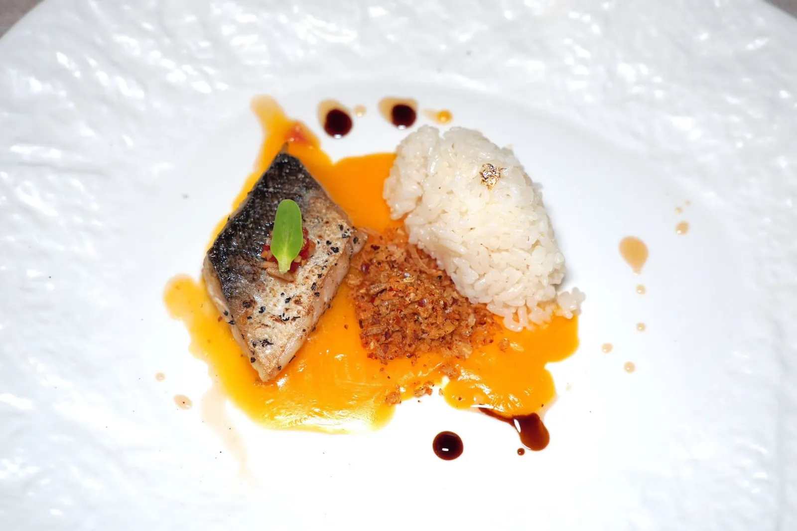 Chapter FiveLost on the RiverSeasonal Fish with Coconut Japanese Riceข้าวปลาแกะคอร์สนี้เชฟตั้งใจนำเสนอปลาพื้นบ้านของไทยอย่างปลาน้ำดอกไม้ซึ่งมีเนื้อสัมผัสที่สู้ฟันเบา ๆ เป็นเอกลักษณ์ เชฟนำไปเซียด้านเดียวฝั่งหนังปลาเพื่อใฟ้เนื้อปลาไม่กระด้าง ซอสตรงกลางได้รับแรงบันดาลใจมาจากซอส Hollandaise ที่มีส่วนผสมของพริกน้ำปลาสูตรพิเศษและครัมเบิ้ลสมุนไพรกรอบ ๆ อีกฝั่งหนึ่งคือข้าวมันญี่ปุ่นหุงด้วยกะทินั่นเอง (12/20)