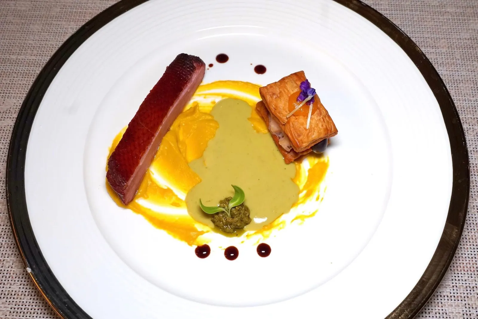 Chapter SevenA Duck in the JungleSmoked Duck Breast with Green Curry Sauceเชฟอาศัยแรงบันดาลใจมาจากช่วงที่เชฟเคยไปแคมปิ้งในป่าโดยการนำเปลือกไม้และไม้ลำไยมารมควันเนื้อเป็ดจนหอม เชฟยังนำเป็ดไปซูวีนาน 1 ชั่วโมงแล้วนำมาอบต่ออีก 1 ชั่วโมง จากนั้นพักไว้ 1 วันแล้วค่อยนำมาเซียก่อนเสิร์ฟจริง ตรงกลาวคือเพียวเรฟักทองและเพียวเรโหระพาอิตาลี จากนั้นพนักงานจะเทราดซอสที่มีรสชาติและความหอมของแกงเขียวหวานลงไปด้วย อีกฝั่งคือ Puff Pastry สอดไส้ตรงกลางเป็นผลไม้หวาน ๆ ตัดรสชาติอันเข้มข้นของแกงได้อย่างพอเหมาะ (13/20)