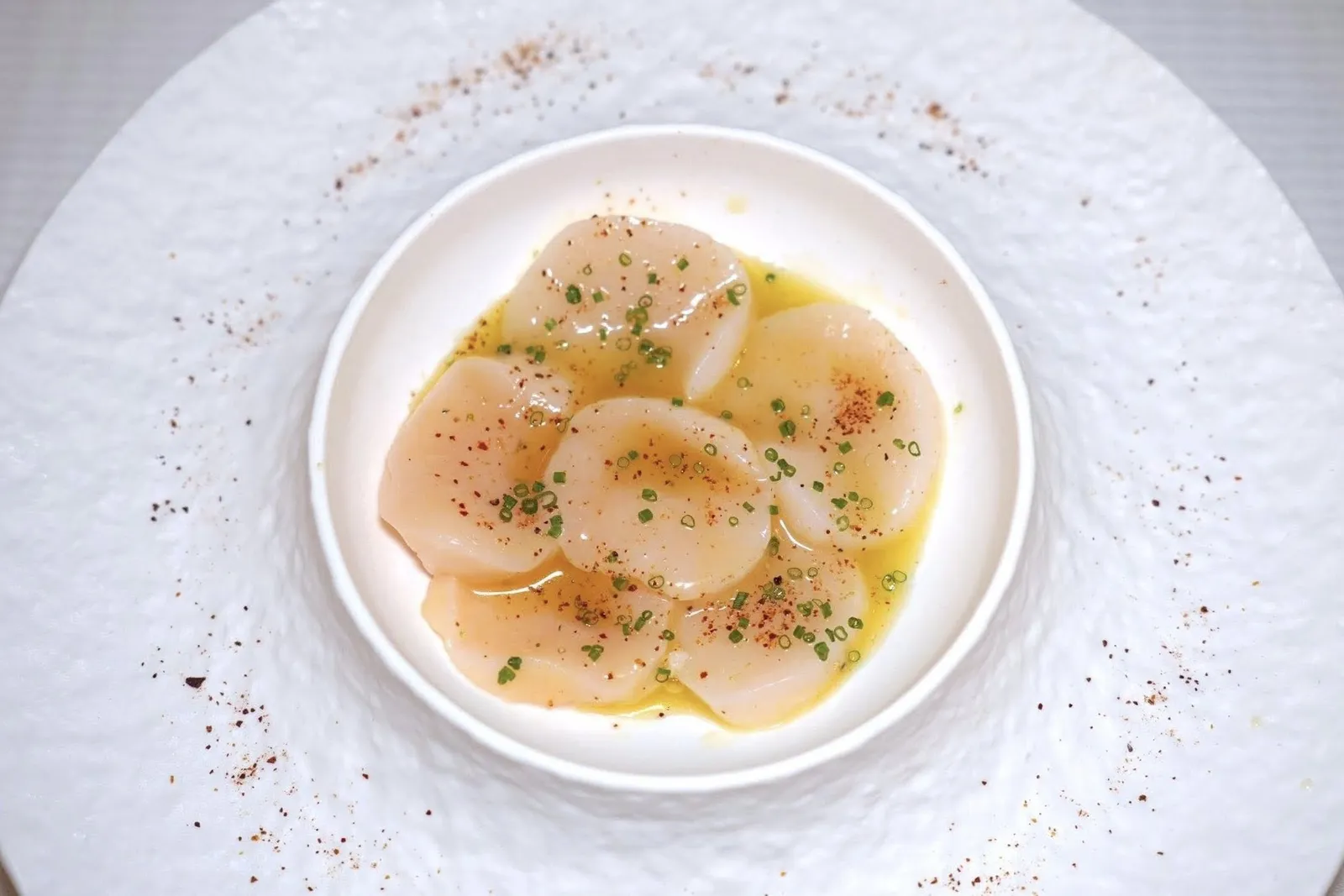HOKKAIDO SCALLOPS (850++)Crudo with chives, espelette peppers powderหอยเชลล์ยักษ์จากจังหวัด Hokkaido แล่เป็นชิ้นแล้วเสิร์ฟมาแบบดิบ จากนั้นปรุงรสด้วยต้นหอมและผงพริก Espelette เพียงเบา ๆ