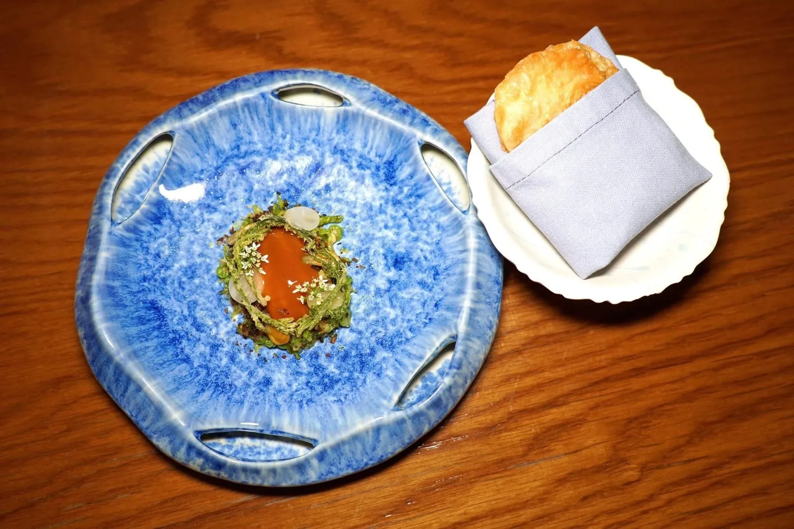 แกงส้มShrimp Mousse / Cha-om / Coconut Shoot / Rotiแกงส้มที่เชฟนำเสนอมาในรูปแบบใหม่ ตรงกลางคือมูสกุ้งท็อปด้านบนด้วยซอสแกงส้ม ด้านล่างคือสลัดผักประกอบไปด้วยถั่วพลู ถั่วฝักยาว และยอดมะพร้าวอ่อน ยังมีชะอมทอดกรอบสร้างมิติทางเนื้อสัมผัสที่ดี นอกจากนี้ยังมียอดมะละกอดิบดองและดอกโสนดองช่วยเติมแต่งรสเปรี้ยว คอร์สนี้เสิร์ฟมาคู่กันกับโรตีกรอบให้รับประทานคู่กัน (15/20)