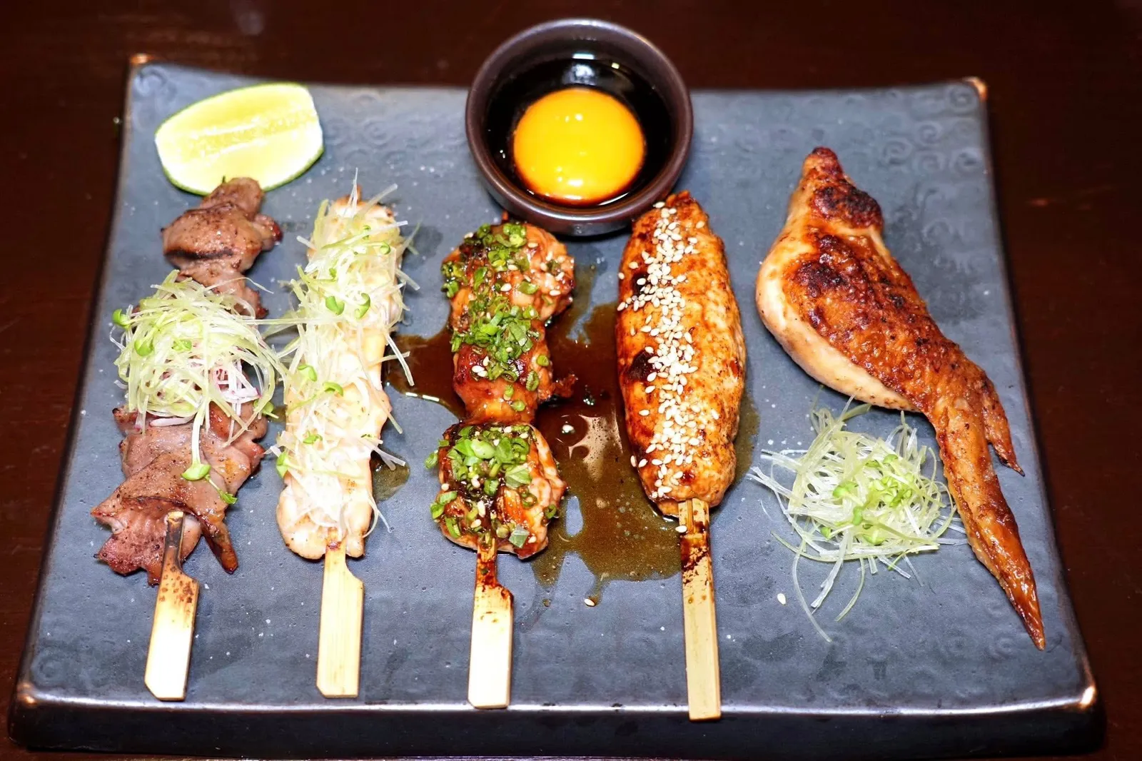 YAKITORI OMAKASE SET (525++)Chef's selected 5 skewersส่วนใครที่เป็นสายอิซากายะต้องไม่พลาด Yakitori ที่มีให้เลือกสั่งทั้งแบบชิ้นและแบบ Omakase Set เริ่มต้นด้วย Sunakimo หรือส่วนกึ๋นของไก่ที่ย่างแล้วทาด้วย Shiotare หรือซอสเกลือ-สาเกรวมไปถึงมีอโรมาหอม ๆ ของพริกไทยดำ ถัดมาคือ Wakatori เนื้อไก่ที่ย่างมาซอสเกลือ-สาเกมาโดยที่เนื้อยังคงไว้ซึ่งความฉ่ำ ยังมี Yuzu Yakitori ที่ใช้ส่วนน่องสะโพกไก่ย่างกับซอสเทอริยากิจับคู่มากับเจลยูซุรสเปรี้ยว ชิ้นกลมรีคือ Tsukune เนื้อไก่บดแล้วย่างจนนุ่มฉ่ำ ด้านบนโรยด้วยงาขาว จากนั้นเสิร์ฟมากับซอสเทอริยากิเข้มข้น สุดท้ายคือ Tebasaki หรือส่วนปีกไก่ย่างกับซอสเกลือ-สาเก