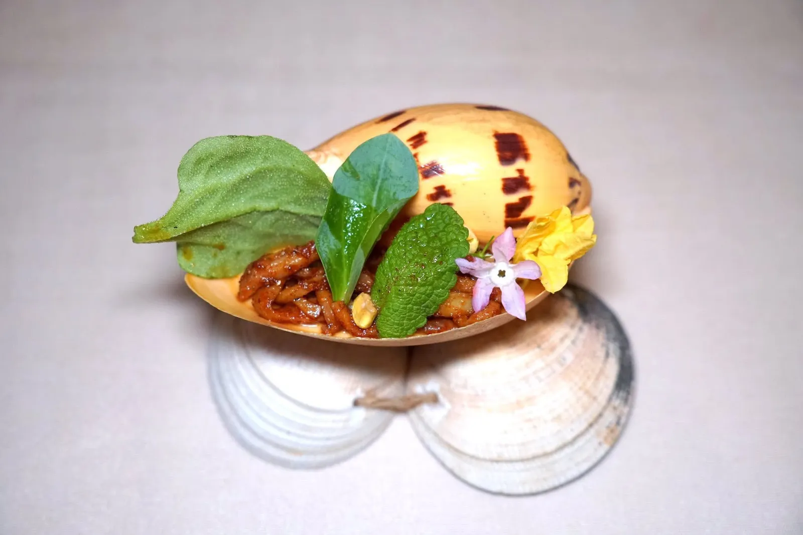 Corn Custard & Sea Snailคัสตาร์ดข้าวโพดนุ่ม ๆ เสิร์ฟมากับเมล็ดทานตะวันและเนื้อหอยที่ผ่านการกงฟีจนสุกพอเหมาะ จากนั้นวางมาในเปลือกหอยทะเล เชฟปรุงรสด้วยโชยุเห็ด สาเกคาซุ และมิรินข้าวโพด ด้านบนยังมีผักสมุนไพร (15/20)