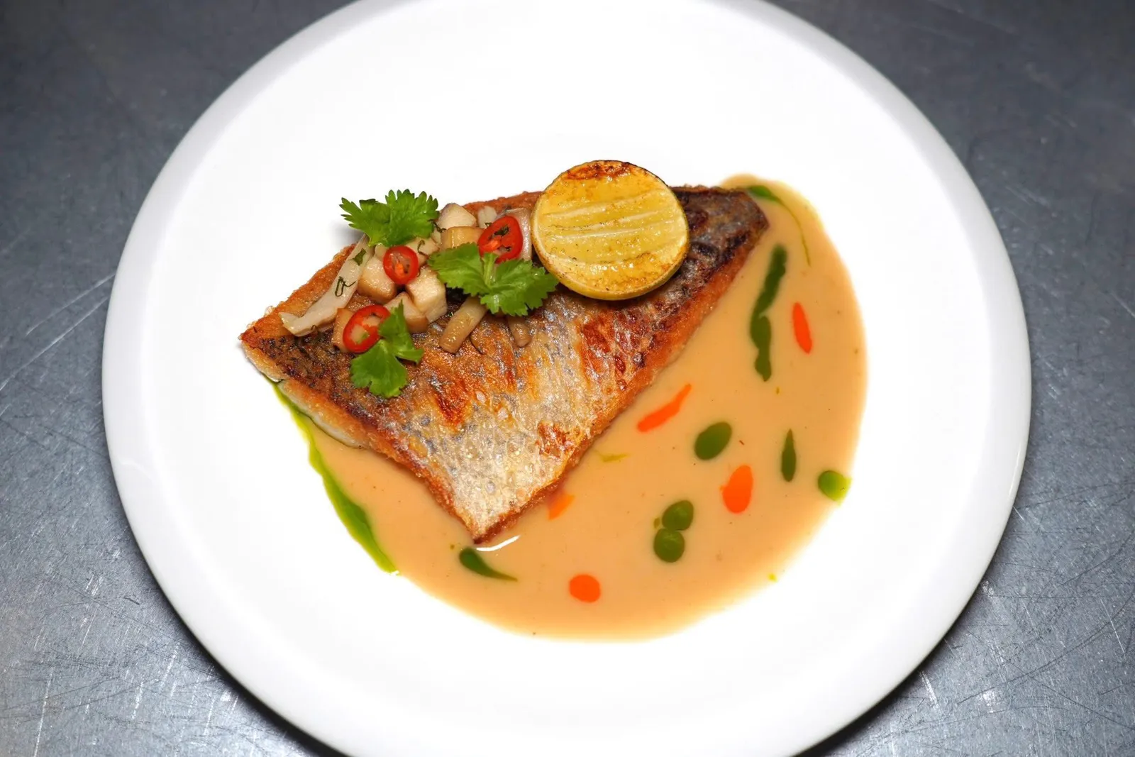 GRILLED SEA BASS (490++)ปลากะพงที่ย่างแล้วเสิร์ฟมาคู่กันกับซอส Beurre Blanc ที่ใส่รสชาติของต้มข่าลงไปด้วยให้รสเปรี้ยวนำและอโรมาหอม ๆ ของเครื่องต้มข่าอย่างมีมิติ