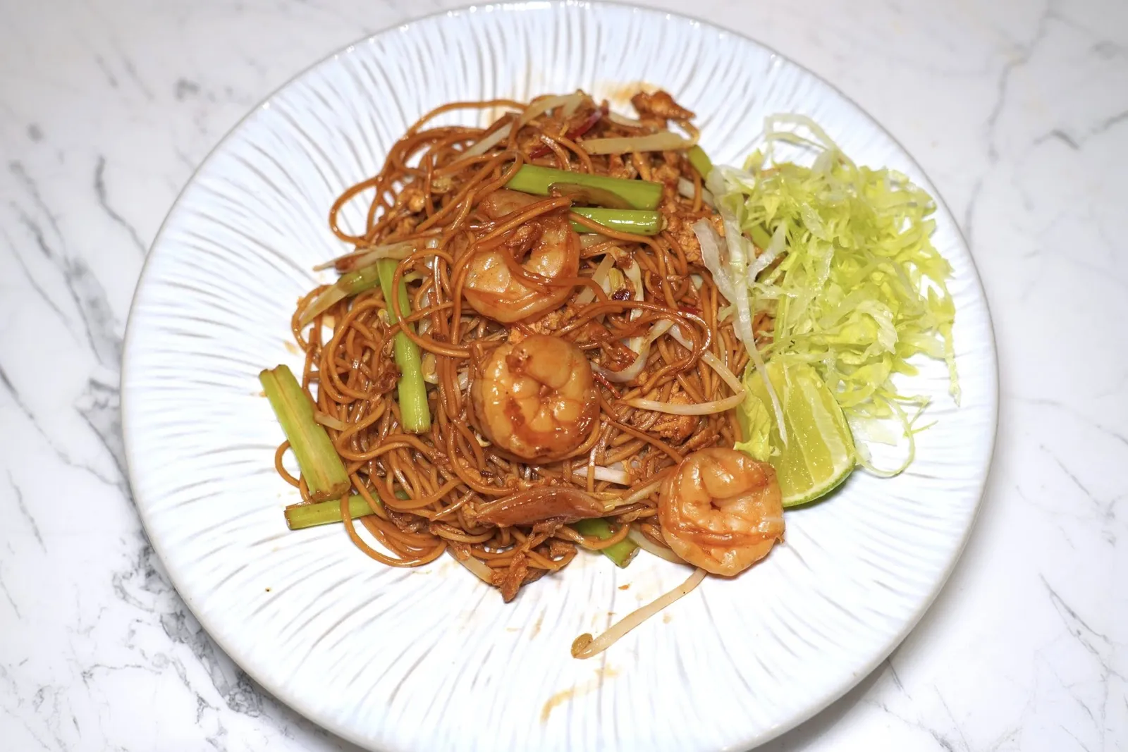 ผัดก๋วยเตี๋ยวสไตล์ฮ่องกงFried Noodles Hong Kong Styleผัดหมี่สไตล์ฮ่องกงให้รสชาติที่ค่อนข้างเค็มเพื่อบาลานซ์ความเปรี้ยวของมะนาว ส่วนโปรตีนหลักในจานคือเนื้อกุ้ง