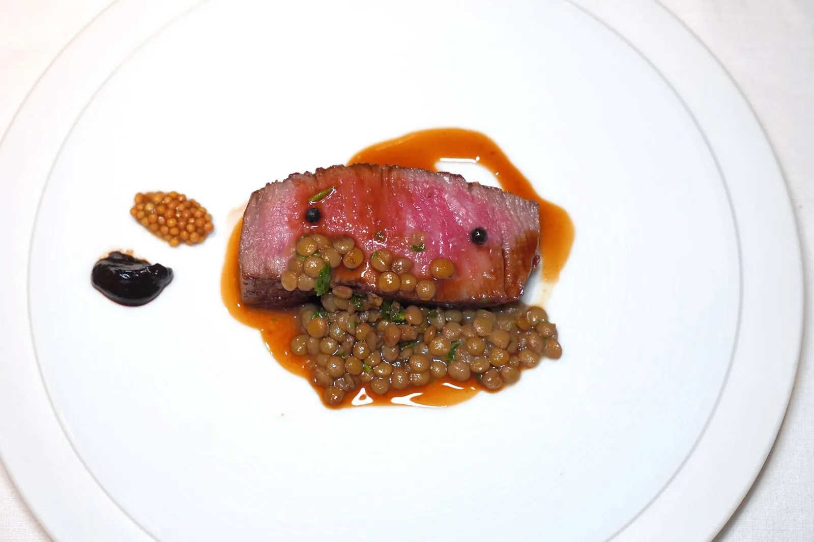 🥄 MAIN DISHA5 Kagoshima wagyu filet steak (500 THB++)เนื้อวัววากิวระดับ A5 เสิร์ฟมากับซอส Jus ที่ผสมผสานน้ำสต๊อกเนื้อและไวน์แดงเข้าด้วยกันจนกลมกล่อม ด้านล่างคือถั่วเลนทิล ข้าง ๆ คือครีมกระเทียมดำและเมล็ดมัสตาร์ด