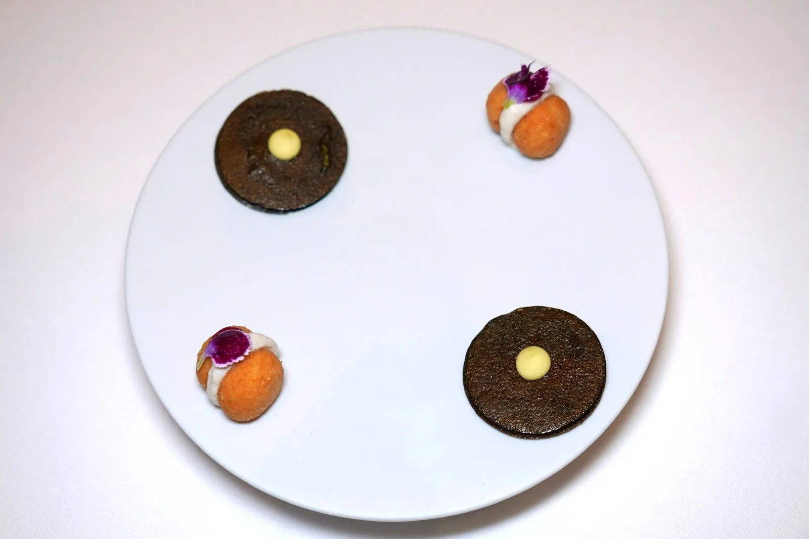 Casa Perbellini amuse-boucheบิสกิตสีดำเตรียมมาจากสาหร่ายโนริ ด้านในสอดไส้ Guacamole ด้านบนคือ Wasabi Mayonnaise ให้ความฉุนพอประมาณ ข้าง ๆ คือ Baci di Dama หรือที่เรียกกันว่า Italian Lady's Kisses ปกติเป็นขนมหวานชนิดหนึ่งแต่เชฟปรับรูปแบบการเสิร์ฟมาเป็นของคาวแทนโดยใช้ครีมพริกไทยจับคู่มากับเจลทับทิม (18/20)