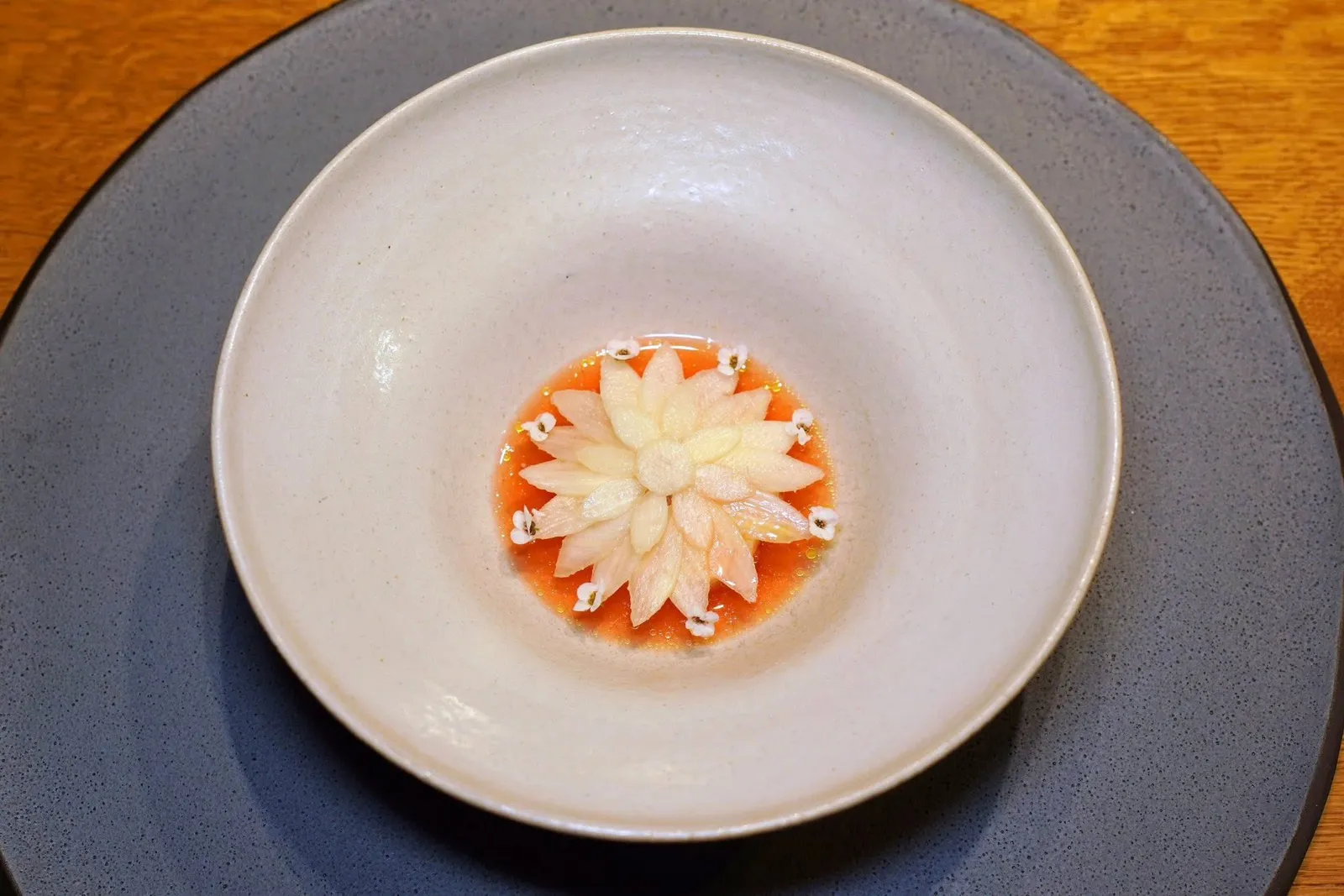 ZANDERwhite asparagus, geraniumปลาแม่น้ำ Zander หมักเพียงเบา ๆ หั่นมาเป็นชิ้นเล็ก ๆ ด้านล่างรองด้วยอีมัลชั่นที่เตรียมมาจากเศษที่เหลือของตัวปลา ซอสรอบ ๆ เตรียมมาจากหน่อไม้ฝรั่งขาวผสมผสานกันกับสตรอว์เบอร์รี่หมักให้สีแดงระเรื่อและรสชาติที่มีมิติ ด้านบนคือหน่อไม้ฝรั่งขาวที่วางเรียงกันอย่างด้วยงามแล้วตกแต่งด้วยดอก Elysium นั่นเอง จากนั้นพนักงานจะเติมน้ำมัน Geranium ลงไปในจาน (19/20)