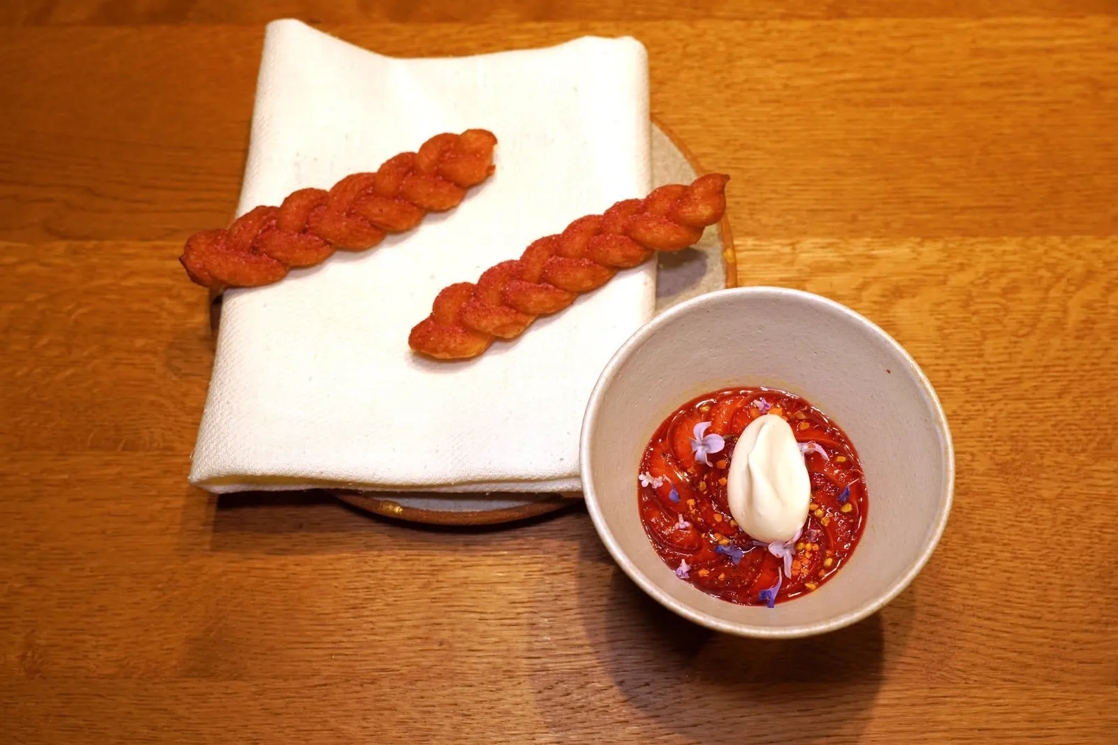 STRAWBERRYtrdinka corn, hayสตรอว์เบอร์รี่เป็นผลไม้ที่กำลังอยู่ในฤดูเก็บเกี่ยวช่วงที่เราแวะไปเยือนห้องอาหารพอดิบพอดี ด้านล่างคือคัสตาร์ดข้าวโพด Trdinka ซึ่งเป็นข้าวโพดหลายสีท้องถิ่นที่ปรับตัวเข้ากับอุณหภูมิอันหนาวเย็นของประเทศสโลวีเนีย ด้านบนคือสตรอว์เบอร์รี่ที่ผ่านการ Glazed ด้วยน้ำมะเขือเทศ ด้านบนคือ Consommé สีแดงที่เตรียมมาจากสตรอว์เบอร์รี่ ดอกไม้ตามฤดูกาล เกสรผึ้ง และมูสสีขาวที่เตรียมมาจากหญ้าแห้งที่เก็บเกี่ยวครั้งแรก (First Harvest) ข้าง ๆ กันคือ Strauben ซึ่งเป็นขนมทอดท้องถิ่นจากแถบ Tirol เหนือโดบเชฟได้เตรียมขึ้นมาให้มีส่วนผสมของแกรปป้า (Grappa) และเบียร์ท้องถิ่นอยู่ในแป้งด้วย ด้านบนคือผงราสเบอร์รี่แห้งและพริก พนักงานแนะนำให้ใช้ Strauben ในการกวาดหรือจิ้มลงไปในถ้วยได้เลย (18/20)