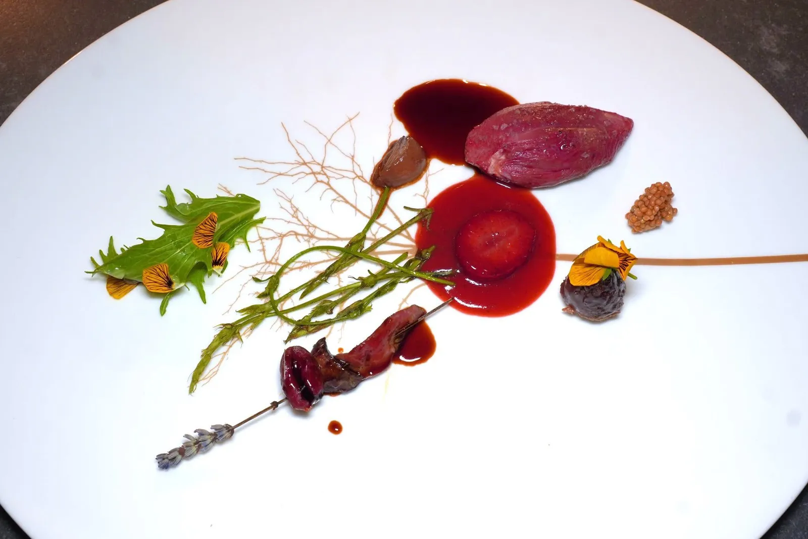 Pigeon ”Giusti“ with strawberries, mustard seeds and tassel hyacintนกพิราบย่างถ่านแล้วเสิร์ฟมาที่ความสุกแบบ Rare ด้านบนโรยเพียงเกลือและพริกไทยเบา ๆ ข้าง ๆ กันคือหัวใจ ตับ และส่วน Fillet เสียบไม้ย่างมาสุกพอเหมาะ ยังมีส่วนขานกปรุงสุกในอุณหภูมิไม่สูงนักให้ความนุ่มและฉ่ำที่ลงตัว นอกจากซอส Jus นกพิราบที่ใส่ราติของ Port Wine ลงไปแล้วเชฟยังใส่ซอสสตรอว์เบอร์รี่และชิ้นสตรอว์เบอร์รี่สร้างรสหวานที่มีมิติ สุดท้ายคือองค์ประกอบของเมล็ดมัสตาร์ดและสมุนไพร Tassel Hyacint (17/20)