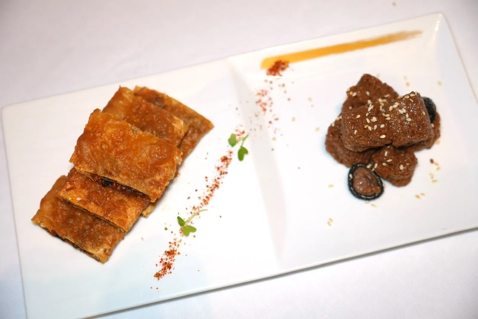金钱菇四喜烤麸,腐衣脆素鹅 (125 CNY+)Braised Shanghainese sponge puff with money mushroom and bean curd, Deep fried crispy bean curd skin rollเมนูมังสวิรัติสไตล์เจียงหนานเสิร์ฟมาเป็นเห็ดเหรียญทองและ Sponge Puff เนื้อสัมผัสดีงามตุ๋นโดยมีรสชาติอันกลมกล่อมของซีอิ๊วและเครื่องปรุง ข้าง ๆ กันคือเนื้ออาหารเจที่เตรียมมาจากฟองเต้าหู้ซ้อนกันหลายชั้นแล้วทอดจนกรอบปรุงรสเค็มหวานเล็กน้อย (15/20)