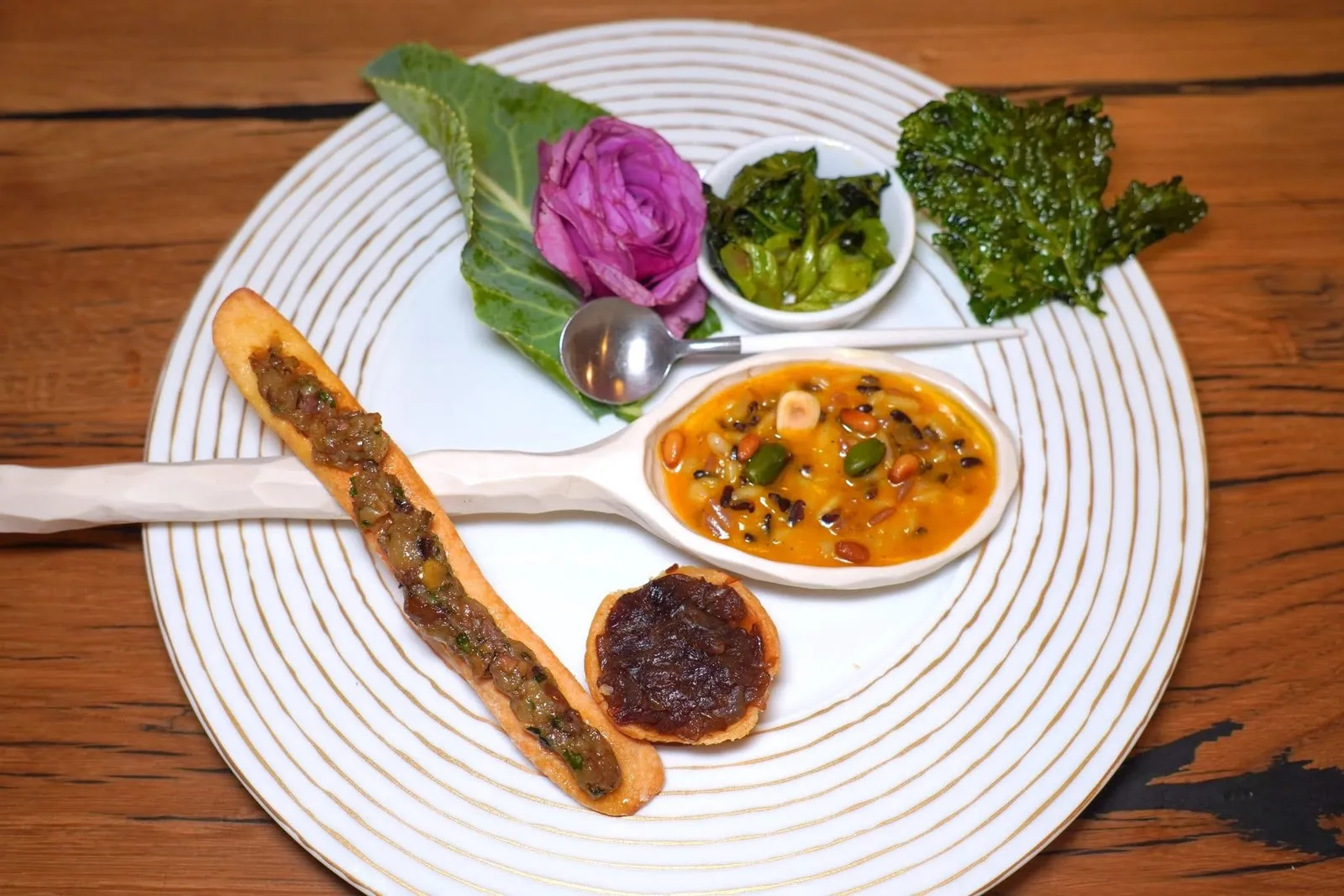 Amuse boucheมินิทาร์ตขนาดพอดีคำบรรจุหัวหอม Tropea ผัดให้รสหวานกลมกล่อม ถัดมาในช้อนไซซ์ยักษ์คือข้าวรีซอตโต้ 2 สายพันธุ์ที่แตกต่างกันของแคว้น Piemont ประเทศอิตาลีคือข้าวขาว Arborio และข้าวดำ Venere สร้างมิติทางเนื้อสัมผัสที่แตกต่างกันได้อย่างโดดเด่นและลงตัว เชฟคลุกเคล้ามากับครีมฟักทองน้ำเต้ารสหวาน ด้านบนท็อปด้วยถั่วพิสตาชิโอ้และเมล็ดสนอบ ถัดมาคือชิ้นยาว ๆ คือบิสกิตน้ำมันมะกอกท็อปด้านบนด้วยองค์ประกอบของมะกอก Taggliche ผสมผสานกันกับกระเทียมจากฝั่งตะวันออกเฉียงใต้ของฝรั่งเศส ทั้งยังมีความหอมของใบเบซิลอีกด้วย ปิดท้ายด้วยผัก Cime di Rapa ทั้งแบบอบและทอดกรอบล้างรสชาติอาหารคำก่อนหน้าได้อย่างหมดจด (16/20)