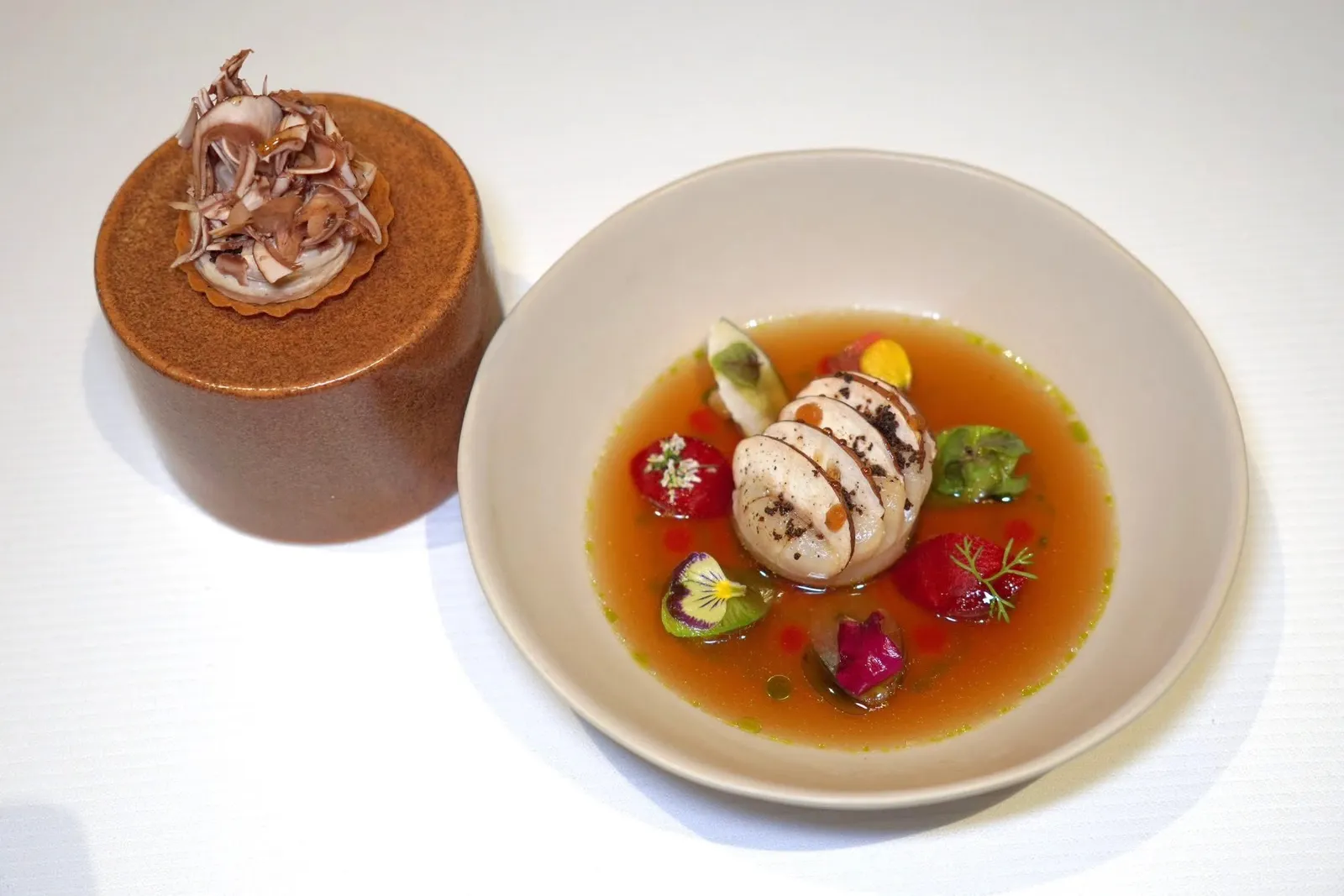 Les Saint Jacques - BrittanyScallop | Wagyu Beef Consommé | MushroomsLes Saint Jacques หรือหอยเชลล์ยักษ์จากแคว้น Brittany เสิร์ฟมากับเห็ด Champignon de Paris ฝานบาง จากนั้นโรยผงเห็ด รอบ ๆ คือผักดองทั้งเทอร์นิป แรดิช และพาสนิปที่มีรสเปรี้ยวกลมกล่อมและมีความกรอบที่พอเหมาะสร้างมิติทางเนื้อสัมผัสที่แตกต่างกันกับชิ้นหอย เชฟตกแต่งด้วยดอกไม้และสมุนไพรต่าง ๆ เช่นดอกสแนปดรากอน ดอกกระเทียม ดอกแพนซี และใบเชอร์วิล (16/20)