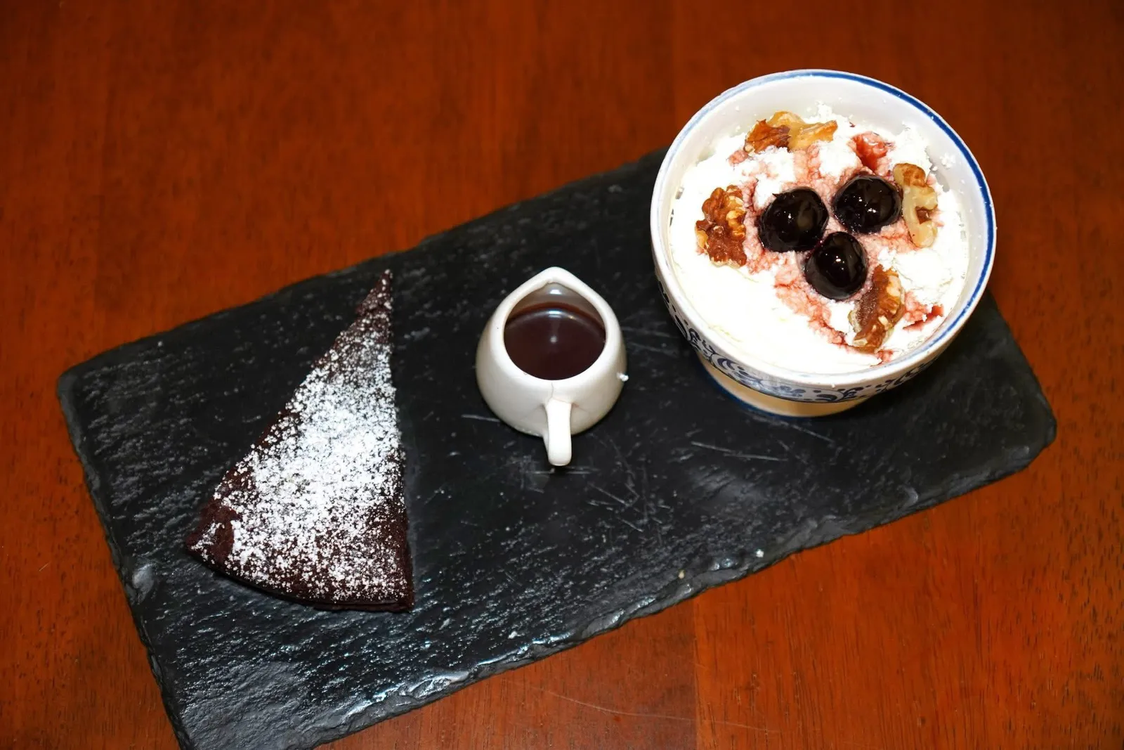 Torta Barozzi Noci e Amarene (320++)Vignola chocolate, almond and walnuts crumble cake served with whipped cream and Italian amarene (sour cherries)Torta Barozzi เป็นของหวานขึ้นชื่อที่ถูกคิดค้นขึ้นโดยเชฟของหวานนามว่า Eugenio Gollini ในปี ค.ศ. 1886 โดยให้ชื่อเพื่อเป็นเกียรติแก่สถาปนิคชื่อดังนามว่า Jacopo Barozzi ตัวขนมมีลักษณะเป็นเค้กช็อกโกแลตกรุบกรอบและมีองค์ประกอบสำคัญคือถั่วอัลมอนต์และถั่ววอลนัทช่วยเพิ่มความกรอบขณะรับประทาน ข้างกันคือวิปปิ้งครีมหอมมันที่มีส่วนผสมของ Amarena cherry อิตาลี ปัจจุบันเมนูนี้ยังคงมีขายอยู่ในร้านขนมหวานต้นตำรับอย่าง Pasticceria Gollini ในเมือง Vignola รวมไปถึงร้านขนมทั่ว ๆ ไปรอบเมือง Modena อีกด้วย (13/20)