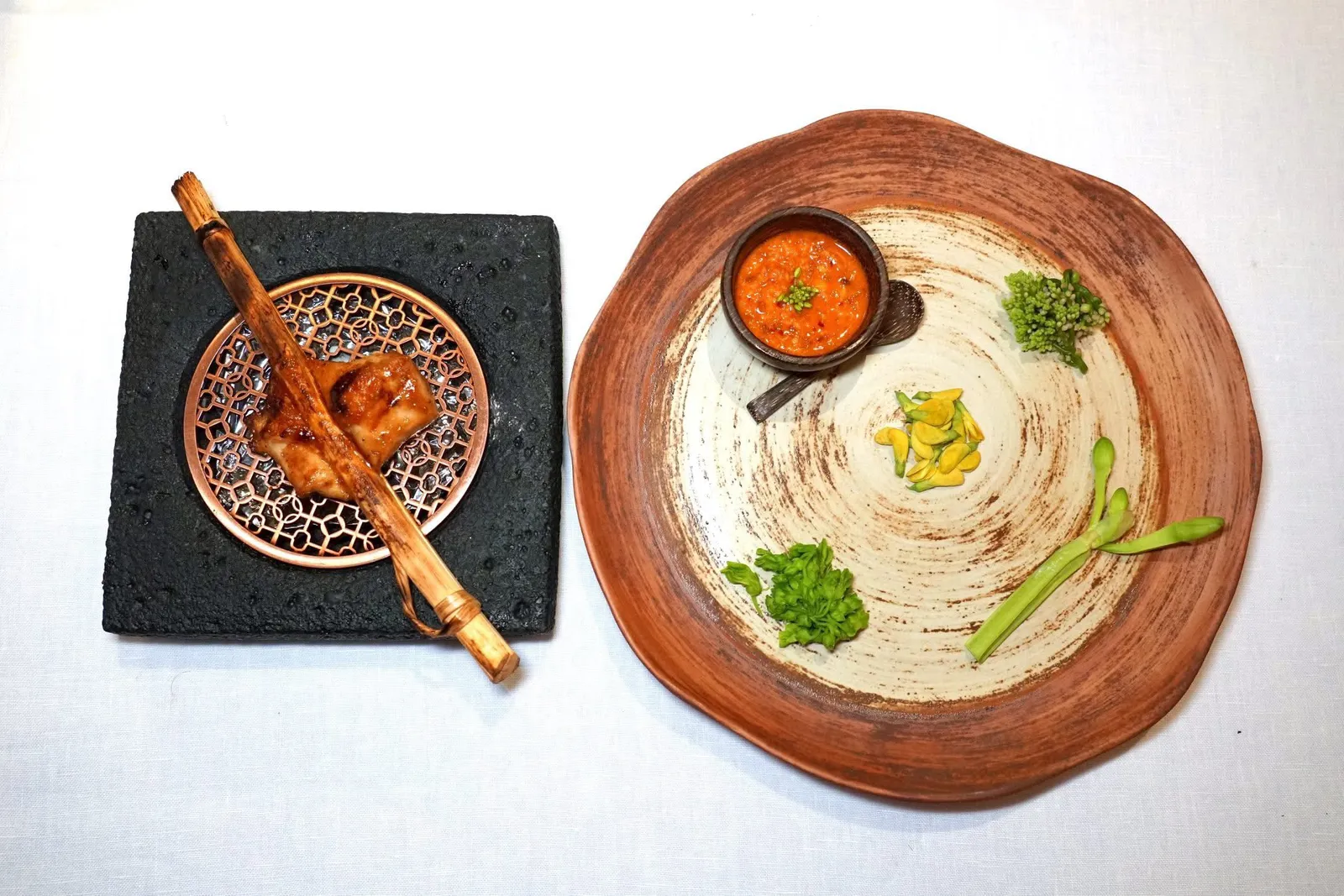 Coconut Chicken with Nam-Prik-Goi-KungCoconut Chicken | Seasonal Flower | Goi's Chili Paste“ไก่กะทิ” เป็นเมนูโบราณที่มีกรรมวิธีการเตรียมดั้งเดิมที่ค่อนข้างลำบากและเกิดข้อถกเถียงกันเป็นอย่างมาก เชฟจึงปรับปรุงรูปแบบการเสิร์ฟใหม่โดยใช้กรรมวิธีเฉพาะตัวคือการฉีดน้ำกะทิเข้าไปที่เนื้ออกไก่จนได้ความหอมและนิ่ม อีกฝั่งหนึ่งคือ “น้ำพริกก้อยกุ้ง” สูตรบ้านบุณยาคมที่มีโขลกเนื้อกุ้งและถั่วลิสงเข้าด้วยกัน ยังมีดอกโสน ผักปลัง ก้านจอง และดอกขจร (14/20)