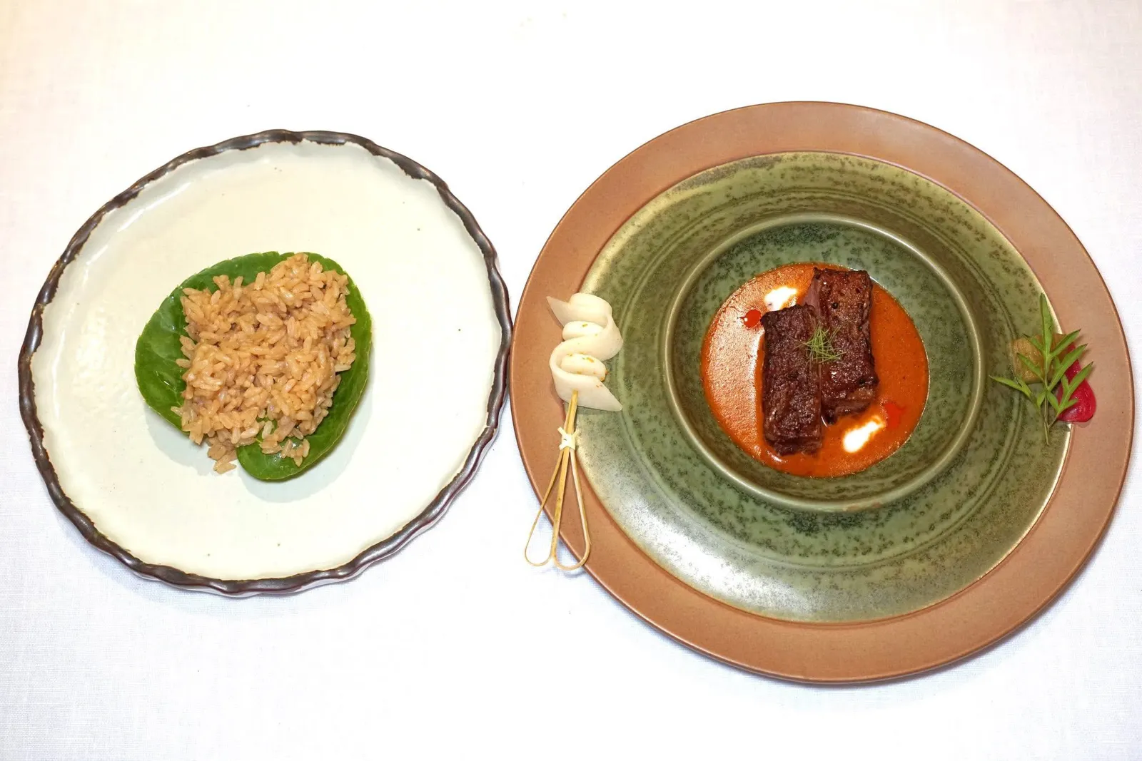 Beef Panang with Kra-Bok RiceLias-gyu's beef | Panang Curry | Eggplant | Kra-Bok Riceพะแนงเนื้อที่อาศัยสูตรต้นตำรับจากพระบรรเจิดวิชาชาญ เชฟเลือกใช้เนื้อวัวไทยเล่ส์-กิวซึ่งเป็นสานพันธุ์ผสมระหว่างชาร์โรเล่ส์ของฝรั่งเศสและวากิว จากนั้นคัดเฉพาะส่วนซี่โครงซึ่งมีจุดเด่นคือเนื้อสัมผัสที่ละมุนลิ้นแต่ยังคงความเป็นเนื้อวัวอยู่มากพอสมควร (15/20)