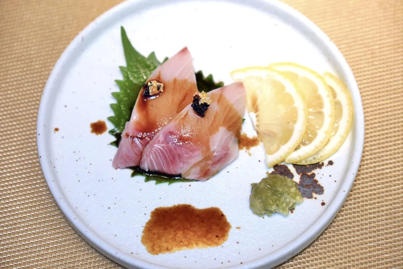 Hamachi Sashimiซาชิมิปลาฮามาจิเสิร์ฟมากับก้านวาซาบิดองและซีอิ๊ว ด้านล่างรองด้วยใบโอบะ
